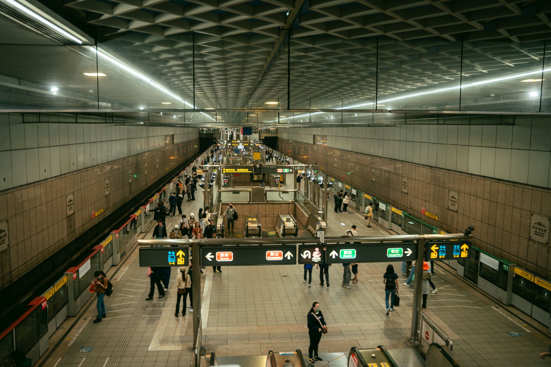 Une station animée du métro de Taipei avec des navetteurs utilisant des escalators et des quais aux heures de pointe.
