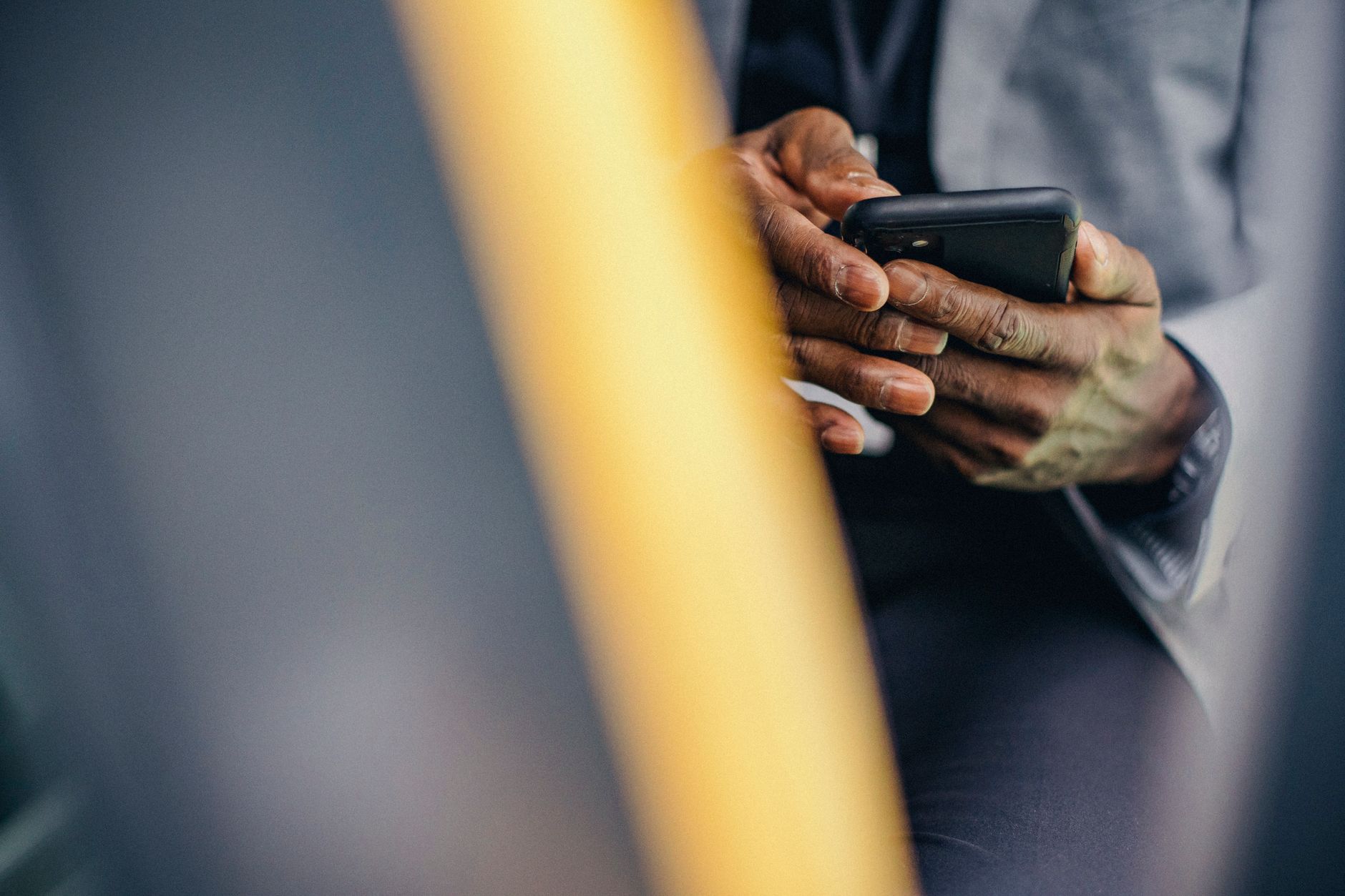 Homme anonyme recadré en tenue formelle assis dans une voiture et naviguant sur un téléphone portable moderne.